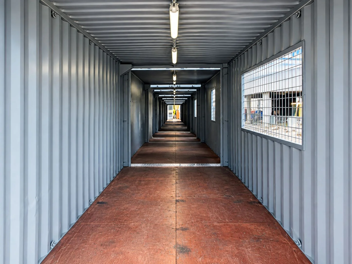 Connected shipping containers used as a protected walkway alongside construction activities at Schiphol